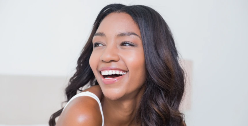 Smiling woman with glowing skin and healthy complexion, showcasing natural beauty and confidence.